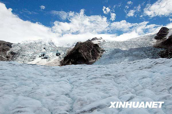 A tourist enjoys the Midui glacier of Tibet on July 31, 2009. Located in Yupu Town, Bomi County, the summit of the glacier is 6,800 meters above sea level and extends about 20 kilometers. The snow line of the glacier mountain is 4,600 meters above sea level. In 2007, local residents opened a Midui glacier travel spot. [Photo: Xinhuanet]