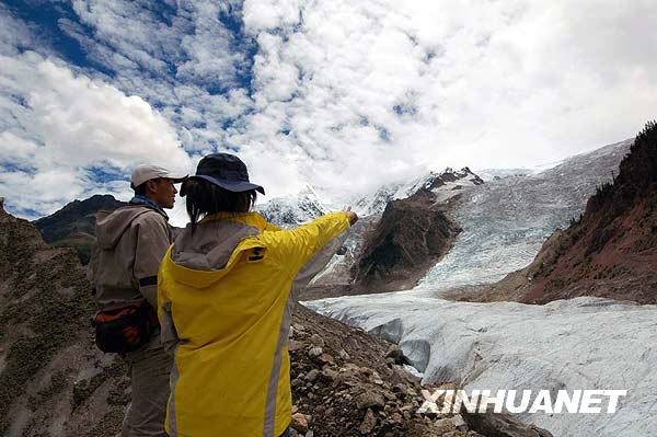 A tourist enjoys the Midui glacier of Tibet on July 31, 2009. Located in Yupu Town, Bomi County, the summit of the glacier is 6,800 meters above sea level and extends about 20 kilometers. The snow line of the glacier mountain is 4,600 meters above sea level. In 2007, local residents opened a Midui glacier travel spot. [Photo: Xinhuanet]