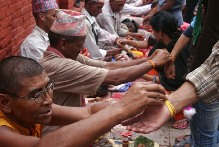 Hindu devotees receive sacred threads around their wrists from the priests during the Janai Purnima festival in the Kumbheswor Temple, on the outskirt of Kathmandu, capital of Nepal, Aug. 5, 2009.[Bimal Gautam/Xinhua]