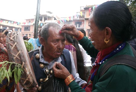 A Hindu devotee receives tika from his relatives during the Janai Purnima festival in the Kumbheswor Temple, on the outskirt of Katmandu, capital of Nepal, Aug. 5, 2009.[Bimal Gautam/Xinhua]