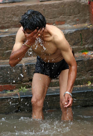 A Hindu man takes holy bath as he observes Janai Purnima festival in the Kumbheswor Temple in Katmandu, capital of Nepal, Aug. 5, 2009.[Bimal Gautam/Xinhua]