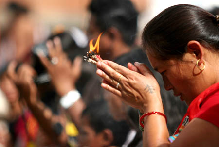 A Hindu devotee worships the lit-butter lamps during the Janai Purnima festival in the Kumbheswor Temple, on the outskirt of Katmandu, capital of Nepal, Aug. 5, 2009.[Bimal Gautam/Xinhua]