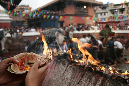 A Hindu devotee lights a lamp while she worships during the Janai Purnima festival in the Kumbheswor Temple, on the outskirt of Katmandu, capital of Nepal, Aug. 5, 2009.[Bimal Gautam/Xinhua]