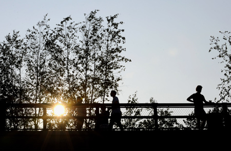 People are silhouetted against sunshine at the High Line Park in Manhattan, New York, the United States, on Aug. 4, 2009.[Xinhua]