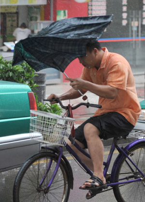 A local struggles in the rain in Guangzhou, capital of south China's Guangdong Province, on Aug. 5, 2009. [Lu Hanxin/Xinhua]