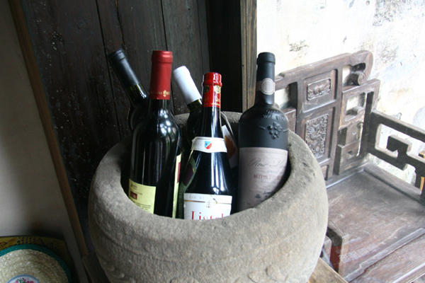 Several bottles of red wine are placed in a corner at Zhulan Bar, an inn in Xidi village, Anhui Province. [Photo: CRIENGLISH.com]