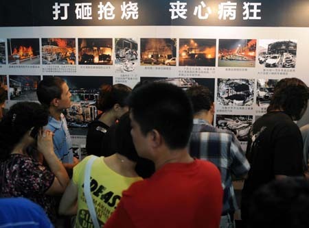 Visitors look at the photos in the exhibition showing how the rioters on July 5 incident in Urumqi were suppressed in Urumqi, capital of northwest China's Xinjiang Uygur Autonomous Region, Aug. 6, 2009.[Sadat/Xinhua]