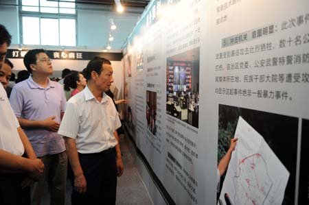 Visitors look at the photos in the exhibition showing how the rioters on July 5 incident in Urumqi were suppressed in Urumqi, capital of northwest China's Xinjiang Uygur Autonomous Region, Aug. 6, 2009.[Sadat/Xinhua]