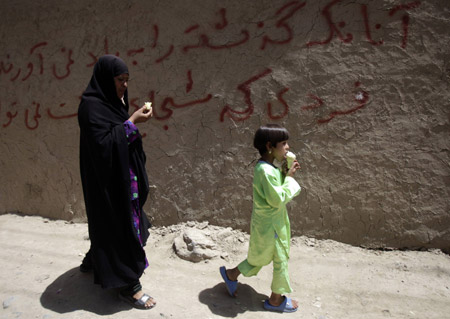 An Afghan woman and girl eat ice cream as they walk down the street in Kabul, August 6, 2009. [Xinhua/Reuters]