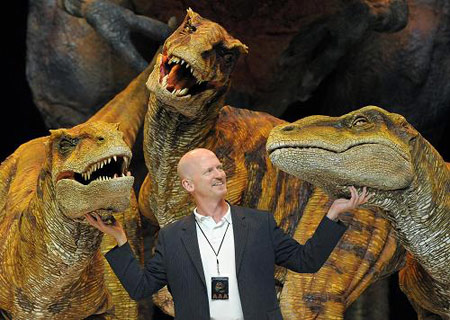 Director Scott Faris poses for photographs with characters from the 'Walking with Dinosaurs' show during a photocall at the O2 Arena in London, Wednesday, Aug. 5, 2009. The show premieres in London tonight and continues touring the UK until Aug. 31.[Xinhua/Reuters]