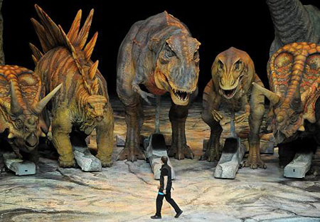 A worker walks past characters from the 'Walking with Dinosaurs' show during a photocall at the O2 Arena in London, Wednesday, Aug. 5, 2009. [Xinhua/Reuters] 