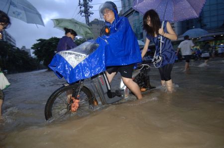 People wade through a flooded street in Haikou, capital of south China's Hainan Province, Aug. 6, 2009. The tropical storm Goni, which landed early Wednesday morning in Taishan of south China's Guangdong Province, has brought heavy rainfall to Haikou, flooding all the main streets of the city. [Zhao Yingquan/Xinhua]