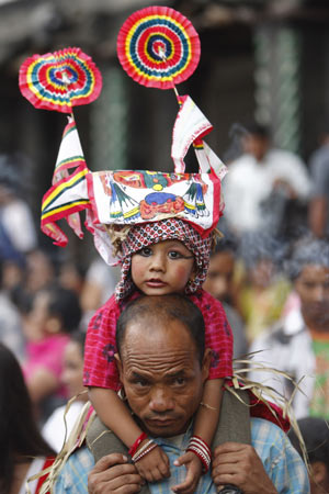 A girl wearing a traditional cow costume, sits on her father's back during the Gaijatra festival parade August 6, 2009.[Xinhua/Reuters]
