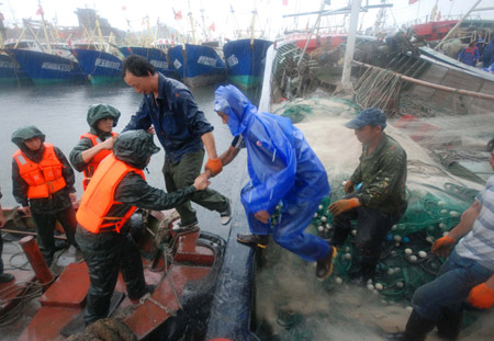 Soldiers help fishermen go to safe zone in the rain in Taizhou City, east China's Zhejiang Province, Aug. 6, 2009. It is predicted that the typhoon Morakot will land off the seashore in east China's Zhejiang Province and southeast China's Fujian Province from Saturday noon to Sunday morning. [Xinhua]