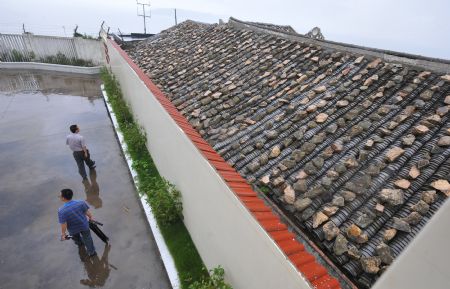 Journalists walk around a stone-covered house in Wenling, east China's Zhejiang Province, on August 6, 2009. The eye of Typhoon Morakot was located at 840 kilometers east off Fuzhou City of southeast China's Fujian Province as of 11 a.m. Thursday.