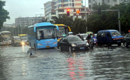 Vehicles drive on a flooded street in Haikou, capital of south China's Hainan Province, Aug. 6, 2009. The tropical storm Goni, which landed early Wednesday morning in Taishan of south China's Guangdong Province, has brought heavy rainfall to Haikou, flooding all the main streets of the city. [Zhou Huimin/Xinhua]