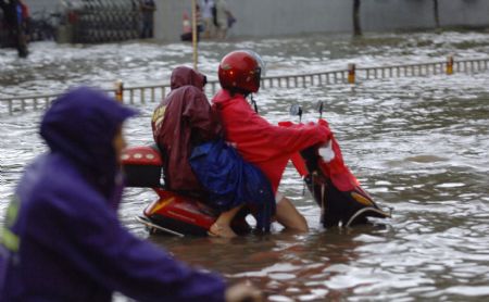 People drive in a flooded street in Haikou, capital of south China's Hainan Province, Aug. 6, 2009. The tropical storm Goni, which landed early Wednesday morning in Taishan of south China's Guangdong Province, has brought heavy rainfall to Haikou, flooding all the main streets of the city. [Zhao Yingquan/Xinhua]