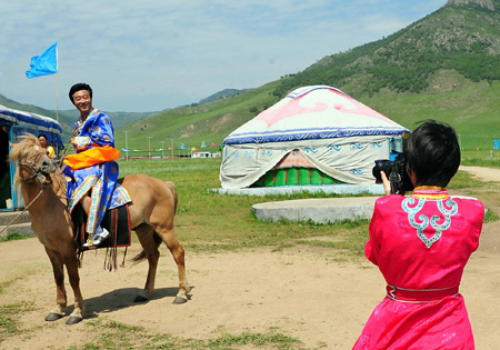 Tourists dressed in Mongolian costumes take photos in front of Mongolian yurts in Horqin Youyi Qianqi, north China's Inner Mongolia Autonomous Region, on Aug. 6, 2009.