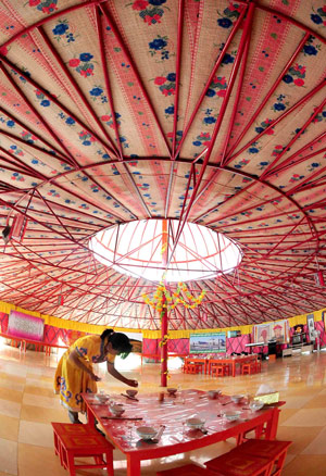 A waitress prepares the dishware set for tourists in a Mongolian yurt in Horqin Youyi Qianqi, north China's Inner Mongolia Autonomous Region, on Aug. 6, 2009. (Xinhua/Wang Song)