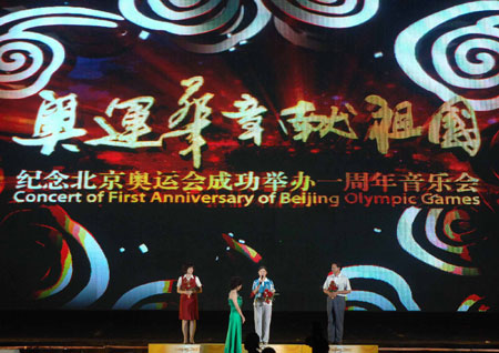 Representatives of Olympic staff(L,1st), volunteers(C) and constructors(R,1st) receive flowers in a musical concert at Beijing Olympic Forest Park to commemorate the first anniversary of Beijing 2008 Olympic Games in Beijing, capital of China, August 6, 2009. [Gong Lei/Xinhua] 