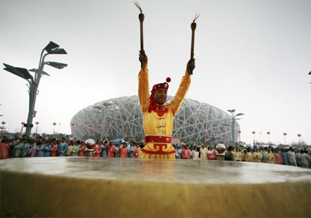 A man performs on a drum outside the National Olympic Stadium, also known as the Bird's Nest, to mark the one-year anniversary of the Beijing Olympic Games, in Beijing August 8, 2009. [China Daily via Agencies]