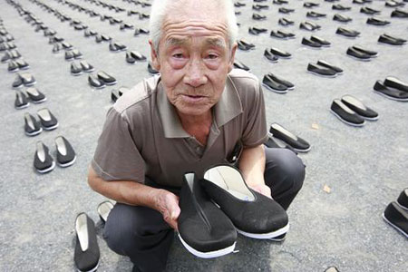 An old man holds one of the 6830 pairs of cloth shoes that placed in a park in memory of the dead Chinese forced laborers in Tokyo, Aug. 9, 2009. [Ren Zhenglaig/Xinhua]