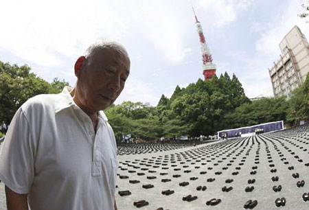 An old man walks past the 6830 pairs of cloth shoes that placed in a park in memory of the dead Chinese forced laborers in Tokyo, Aug. 9, 2009. [Ren Zhenglaig/Xinhua]