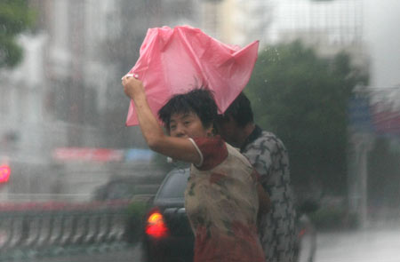 People walk in heavy rain in Jiaojiang of Taizhou city, east China's Zhejiang Province, Aug. 9, 2009. Typhoon 'Morakot' slammed into Chinese provinces on the eastern coast on Sunday, causing casualties, destroying houses and inundating farmlands. [Xinhua]