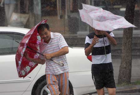 People walk against strong wind in heavy rain on a street in Wenzhou, east China's Zhejiang Province, Aug. 9, 2009. [Xinhua]