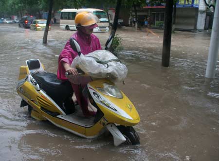 A man pushes the motorbike on a flooded street in Wenling, east China's Zhejiang Province, Aug. 9, 2009. [Xinhua]