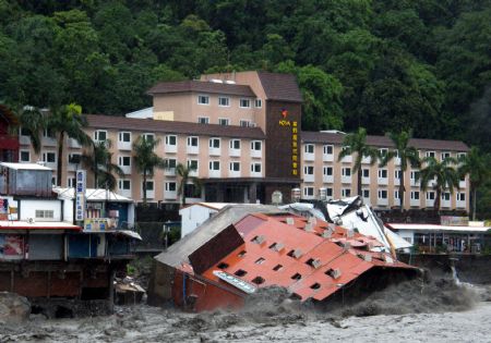 A collapsed hotel building is seen in floods after Typhoon Morakot hit eastern Taiwan August 9, 2009. The six-story hotel collapsed and plunged into a river Sunday morning after floodwaters eroded its base, but all 300 people in the hotel were evacuated and uninjured, officials said. [Xinhua]