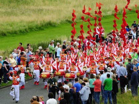 Performers of She Huo, a folk art form of northwest China's Shaanxi Province, parade during the festival cavalcade in Edinburgh, Britain, on Aug. 9, 2009. 84 groups from across the world took part in the annual calvacade celebrating the coming of the one-month festival season at the Holyrood Park in suburban Edinburgh on Sunday. [Xinhua]