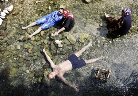 People relax in a hot spring as garra rufa obtusas, also known as "doctor fish", swim around their bodies as part of a treatment process, in Kangal, 105 kilometers (65 miles) south of the central Anatolian city of Sivas August 9, 2009.