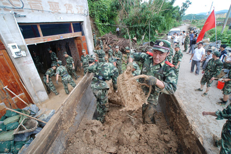Armed policemen help clear roads and houses after a landslide caused by Typhoon Morakot at Kewan Village of Fuding, southeast China's Fujian Province, Aug. 10, 2009. The local government organized the people in the typhoon-stricken area to rebuild their homes on Monday right after the typhoon faded away. [Zeng Zhaohui/Xinhua]