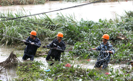 Power technicians draw a wire rope to reestablish power tower destroyed by Typhoon Morakot at Ruian, east China's Zhejiang Province, Aug. 10, 2009. The local government organized the people in the typhoon-stricken area to rebuild their homes on Monday right after the typhoon faded away. [Zhuang Yingchang/Xinhua]