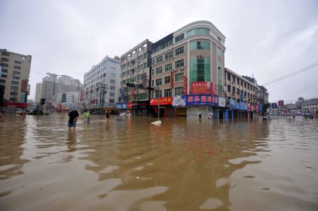 Pedestrians wade through the flooded street in Cangnan, east China's Zhejiang Province, Aug. 10, 2009. Rains brought by Typhoon Morakot, the 8th typhoon of the year, flooded the Cangnan County. [Wang Dingchang/Xinhua]