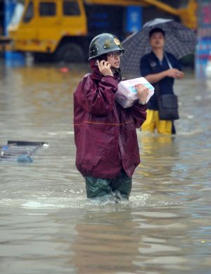 A rescuer makes a phone call in the flooded street in Cangnan, east China's Zhejiang Province, Aug. 10, 2009. [Wang Dingchang/Xinhua]