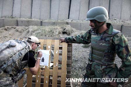 A member of the U.S forces (L) checks the results of an Afghan soldier's shooting with an M-16 rifle on a target sight during training by U.S. forces in Honaker Miracle camp at the Pesh Valley, Kunar Province August 10, 2009. The Afghan National Army has started the process of changing weapons from the old AK-47 to the American M-16 rifle.