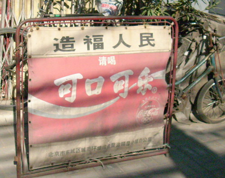 An ad for Coca Cola which translates to: ' To benefit the people, please drink Coca Cola.'