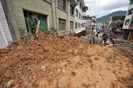 Rescue staff walk on the site where a building is buried by a landslide at Pengxi Township in Taishun County, east China's Zhejiang Province, August 11, 2009. Two people died and four were injured in a storm-induced landslide late Monday here. The landslide occurred at around 10:21 p.m., after five straight days of continuous rain brought by Typhoon Morakot. [Wang Dingchang/Xinhua]