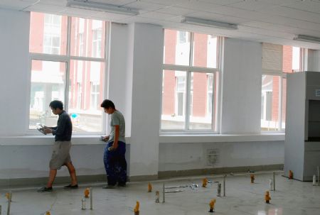 Two workers make the final touch of the interior construction of a classroon of Tianjin High Middle School in Lueyang, northwest China's Shaanxi province, Aug. 12, 2009.(Xinhua/Wang Wei) 