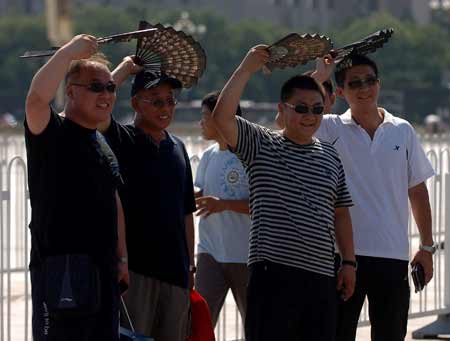 Tourists walk with fans against sunshine in Beijing, cpital of China, Aug. 12, 2009. [Xinhua]