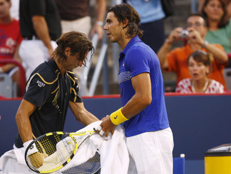 Rafael Nadal, right, from Spain, walks past compatriot David Ferrer as Ferrer packs his gear during the second round of play at the Rogers Cup tennis tournament Wednesday, Aug. 12, 2009, in Montreal. Ferrer pulled out in the first set with a knee injury.