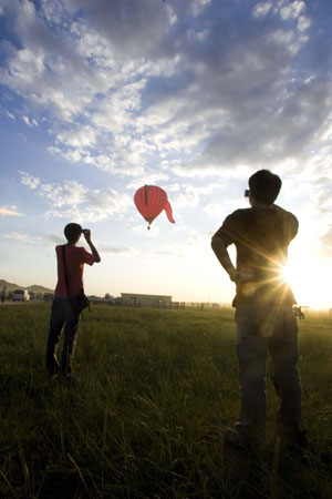 People take photos of a rising hot-air balloon in Guyang County of Baotou City, north China's Inner Mongolia Autonomous Region, on Aug. 12, 2009. 