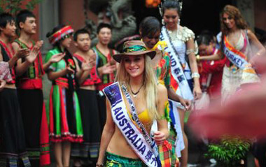 Miss Tourism candidates take a tour around Tusicheng, a folk culture zone of Enshi City in central China's Hubei Province, Aug. 12, 2009. Forty-one contestants participating in the final of 2009 Miss Tourism Queen International took a tour in Enshi City on Wednesday and took part in charity activities during their stay.