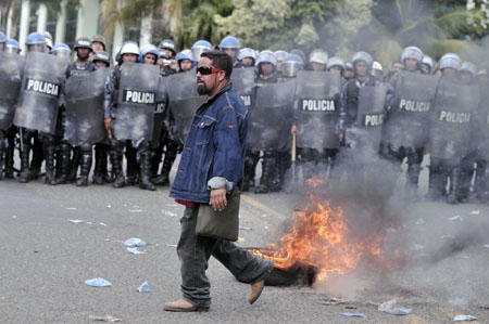 A supporter of ousted Honduran President Manuel Zelaya walk by armed police in Tegucigalpa, capital of Honduras, Aug. 11, 2009. 