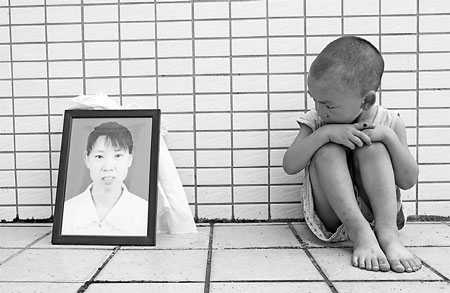 Zeng Lu looks at his mother's portrait by the side of the Tiangongdian police station last Thursday. His mother was killed by a hotel owner after she argued with a waitress at the hotel over the boy picking a plastic flower in the lobby. Zhong Zhibing