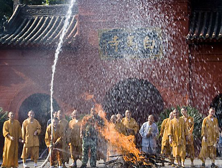 A monk uses the fire hydrant to practice extinguishing fire at the white horse temple, also known as Baimasi, in Luoyang, central China's Henan province, August 13, 2009. [Xinhua] 