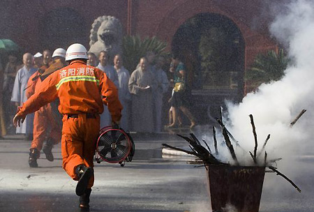 Fireproofing officers teach monks how to put out a fire, at the white horse temple, in Luoyang, central China's Henan province, August 13, 2009. [Xinhua]