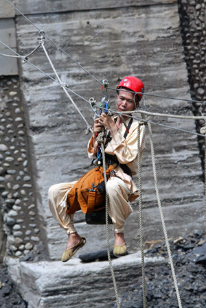 A rescuer moves along cables slung above a destroyed bridge so as to get into the village of Xinkai and rescue trapped villagers in Kaohsiung of Taiwan, August 12, 2009. [Xinhua]